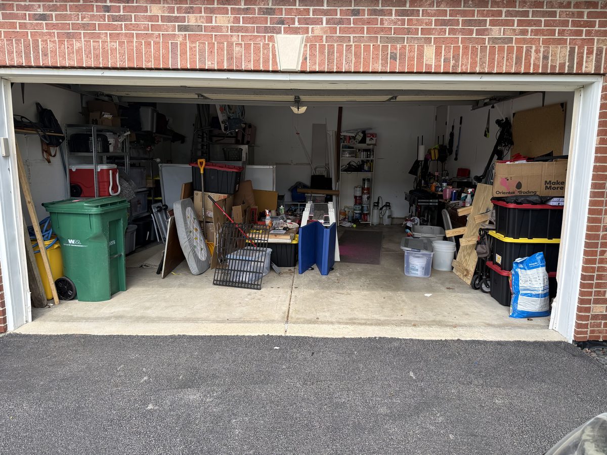 Two-car garage in Lockport before coating — cluttered, stained bare concrete slab